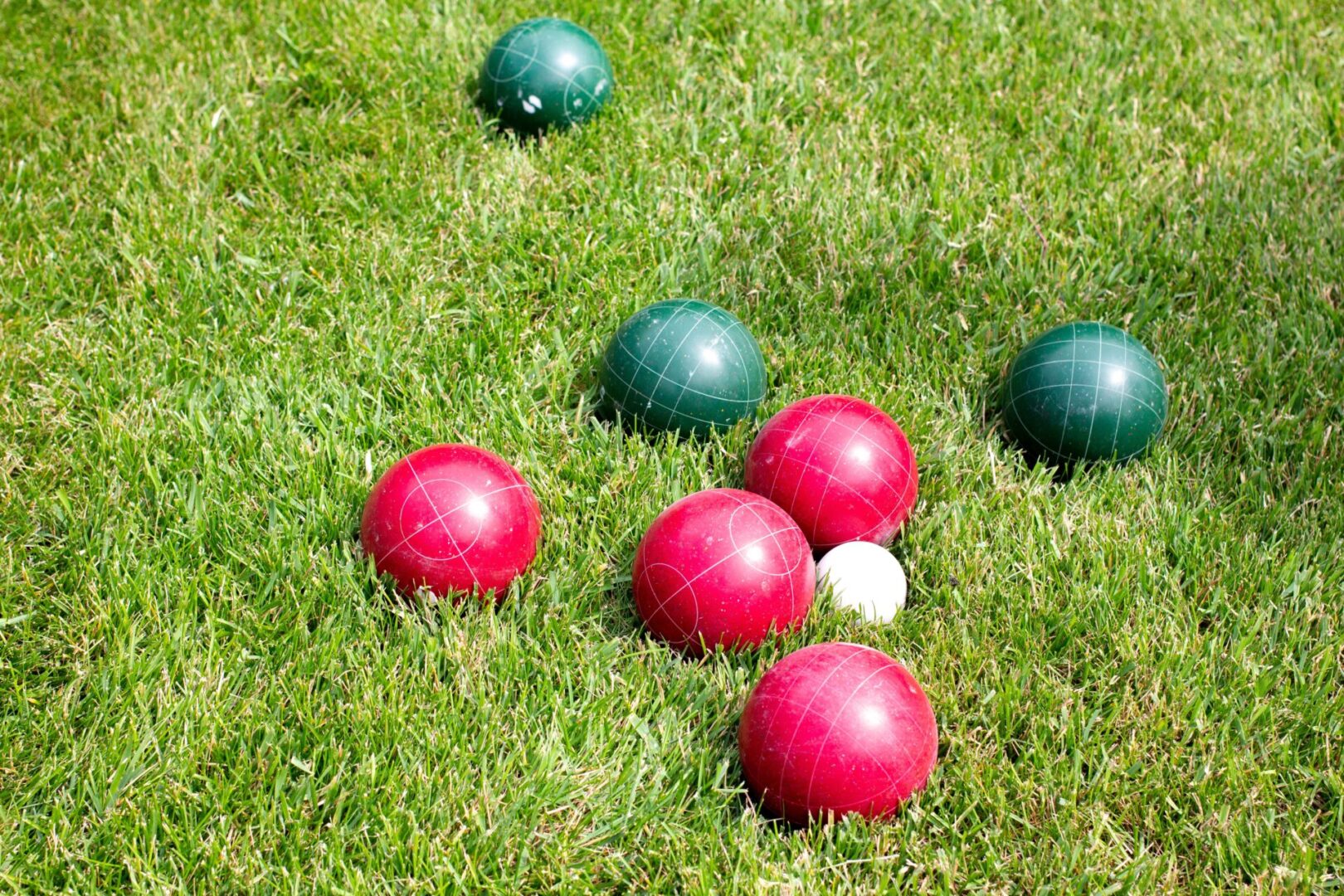 A group of red and green balls in the grass.