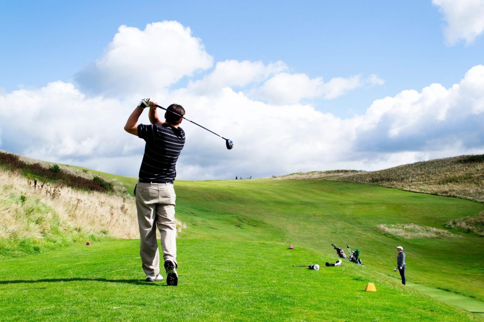 A man swinging at a golf ball on the green.