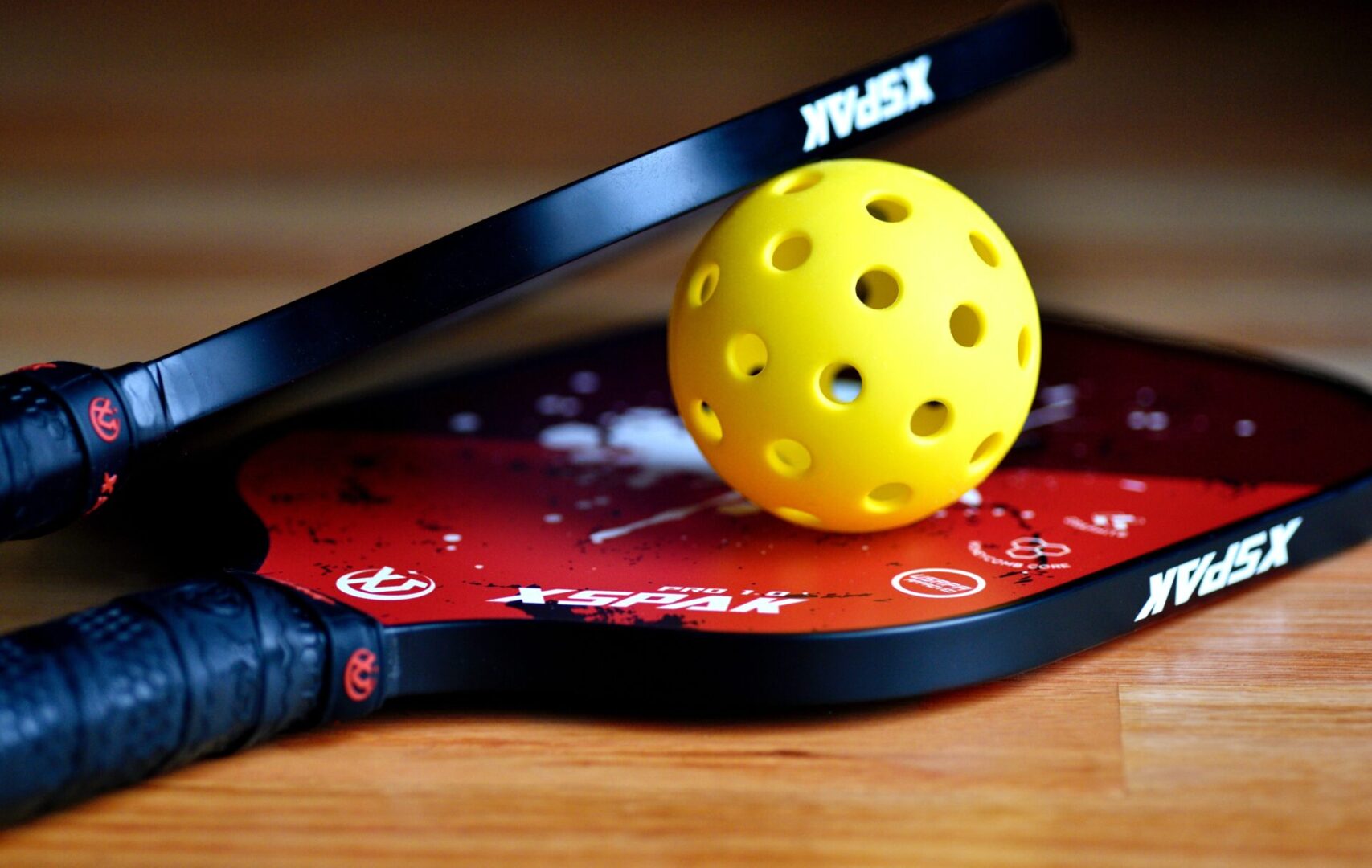 A yellow ball and two rackets on top of a table.