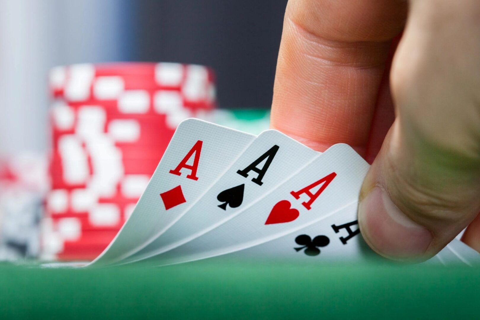 A person holding four aces on top of a green table.